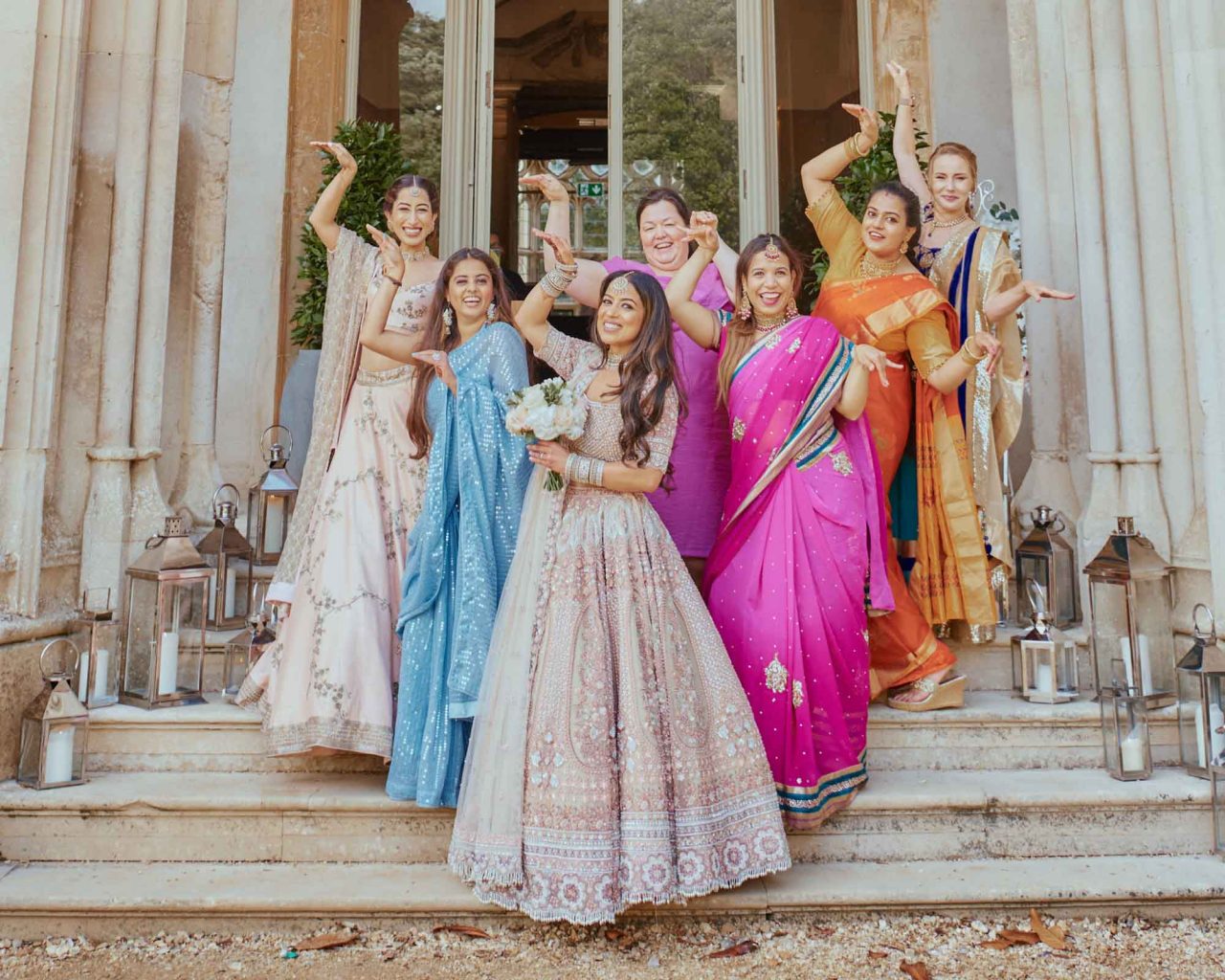 Bride having fun with guests on the steps of Highcliffe Castle in Dorset during an Indian Fusion wedding