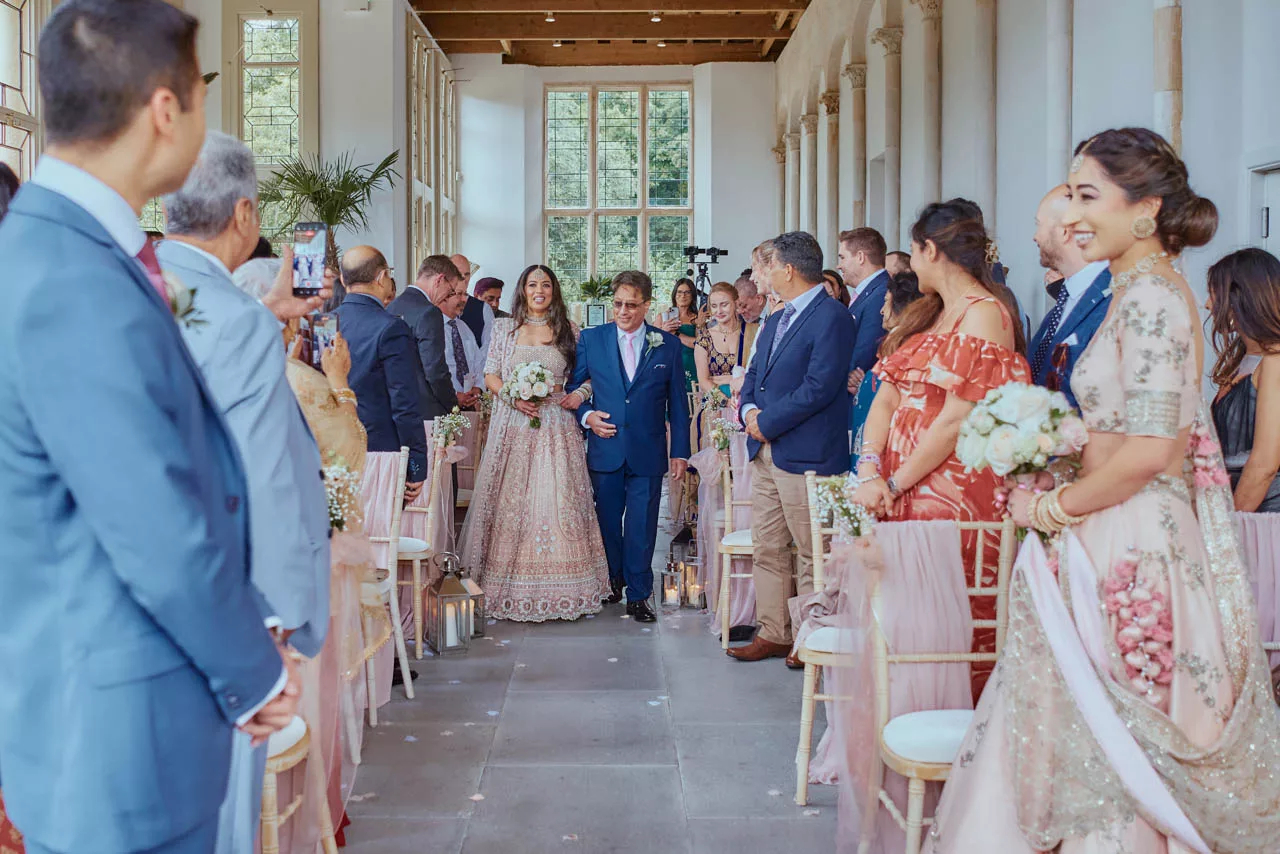 Bride walking down the isle during Indian Fusion Wedding ceremony at Highcliffe Castle in Dorset