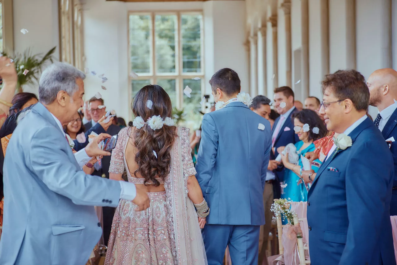 Guests throw confetti down the isle during Indian Fusion Wedding ceremony at Highcliffe Castle in Dorset