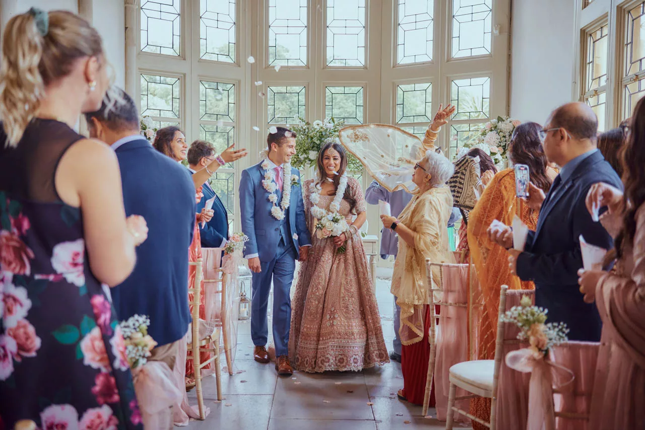Guests throw confetti down the isle during Indian Fusion Wedding ceremony at Highcliffe Castle in Dorset