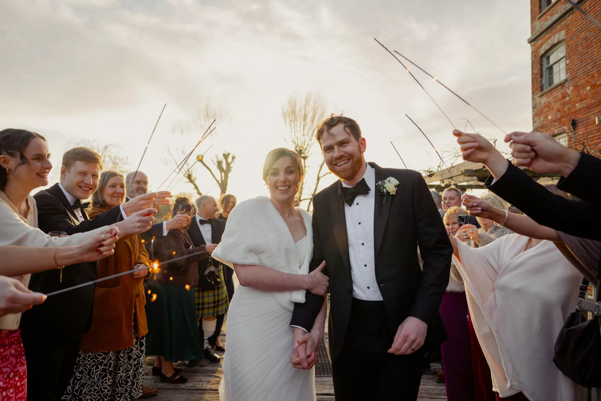 Bride & Groom smiling with sparklers at sunset during a Black Tie wedding at Sopley Mill in 2026