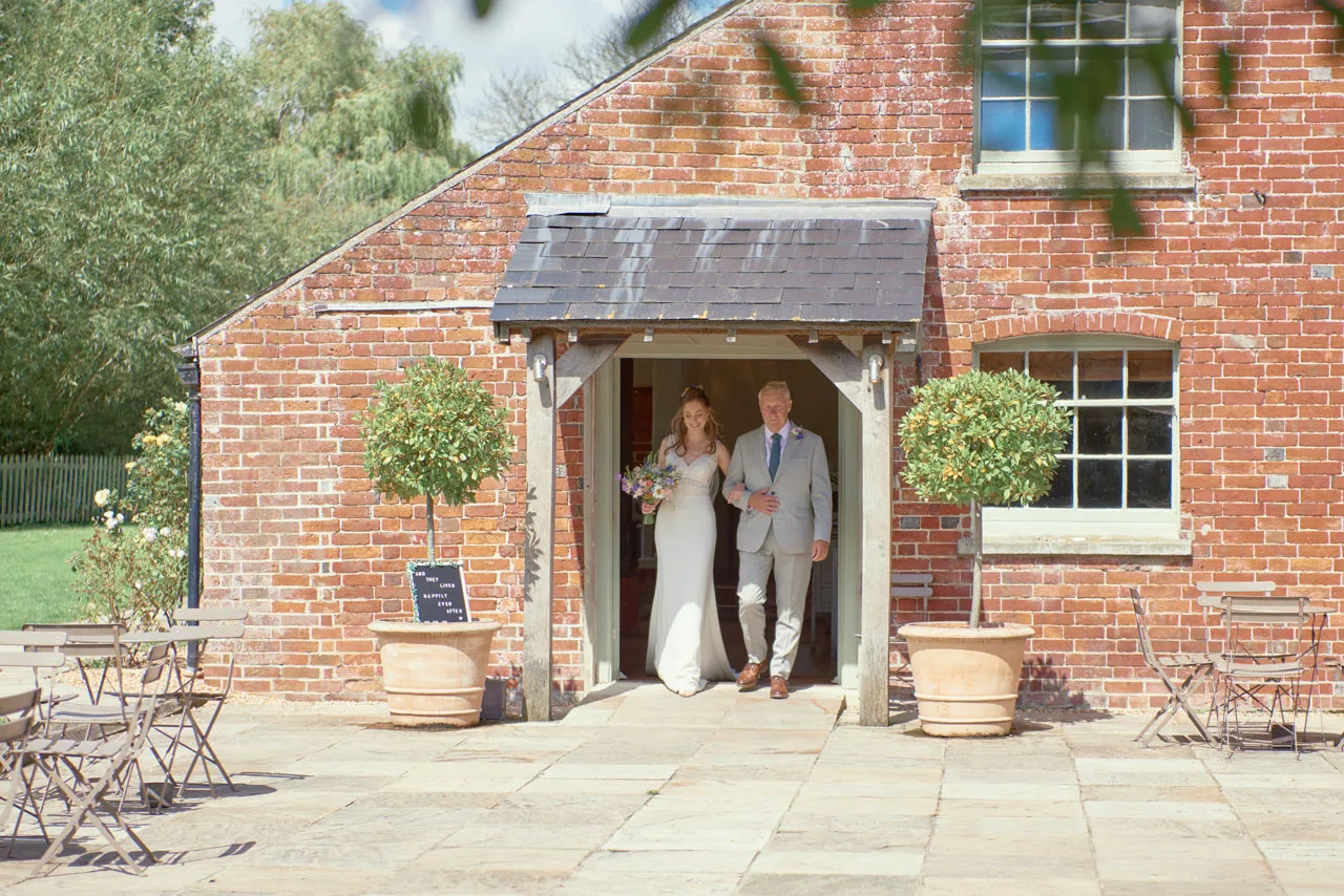 Bride walking to the Ceremony from the Boat Room during an outdoor wedding at Sopley Mill