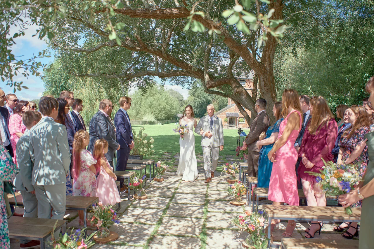 Bride walking down the isle during an outdoor wedding ceremony at Sopley Mill