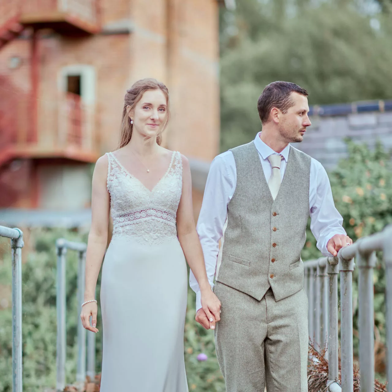 A beautiful and elegant natural editorial style image of a bride and groom wearing green tweed suit on the bridge at Sopley Mill wedding venue