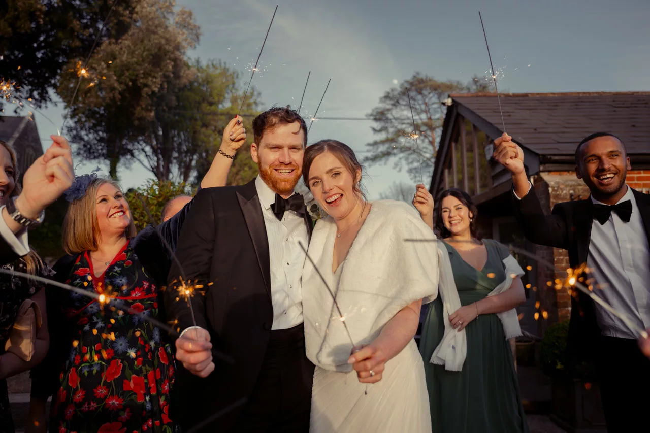 Bride & Groom smiling with sparklers at sunset during a Black Tie wedding at Sopley Mill in 2026