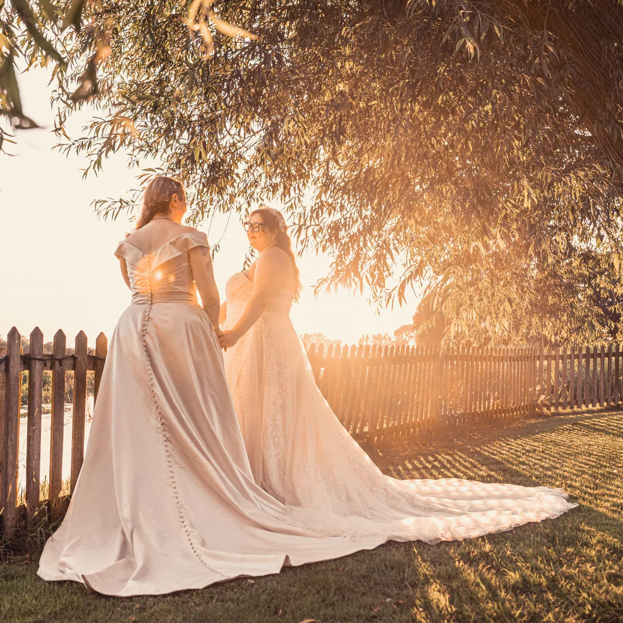 Two Brides in golden hour light in the outside wedding area under the trees at Sopley Mill at sunset