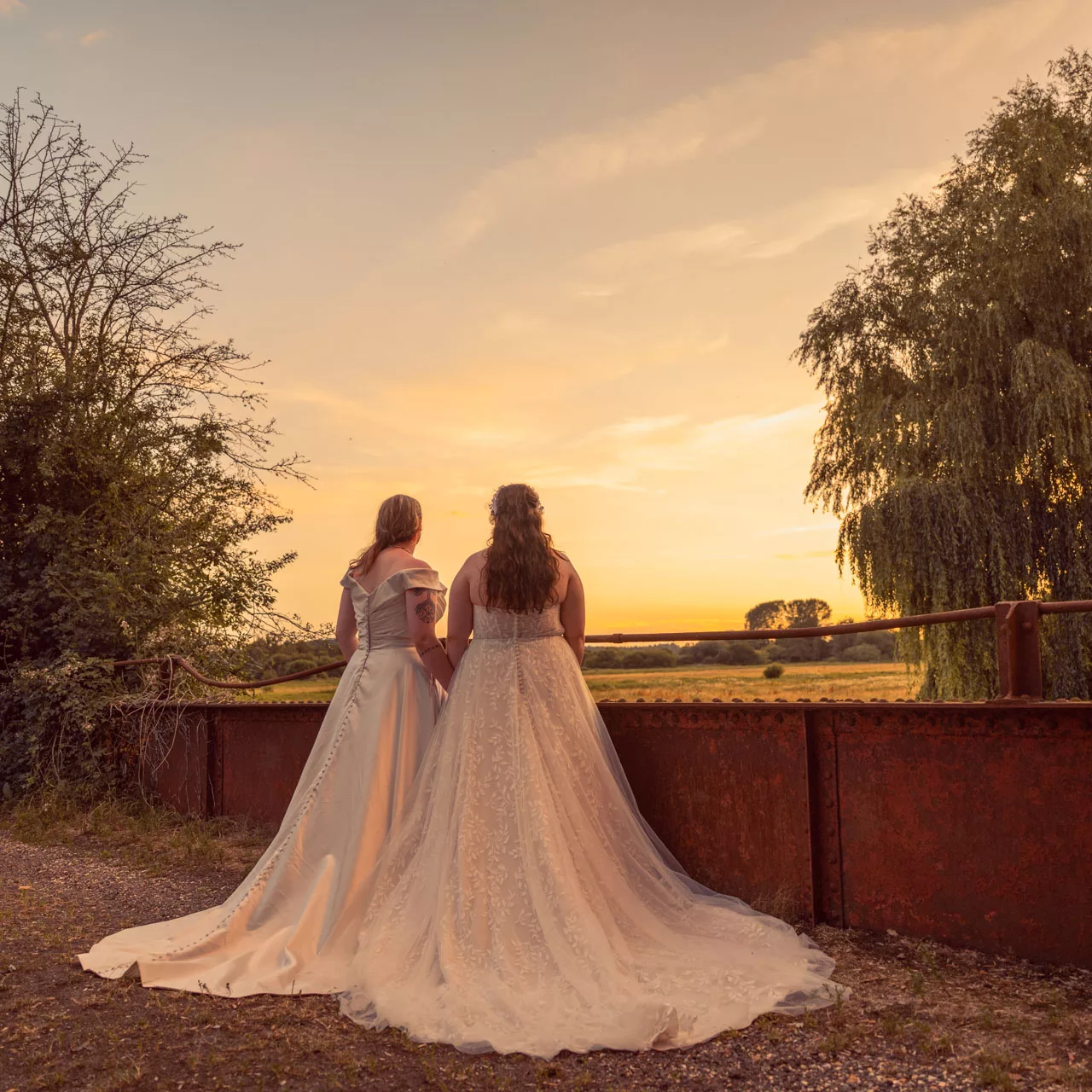 Two Brides in golden hour light on the bridge at Sopley Mill at sunset