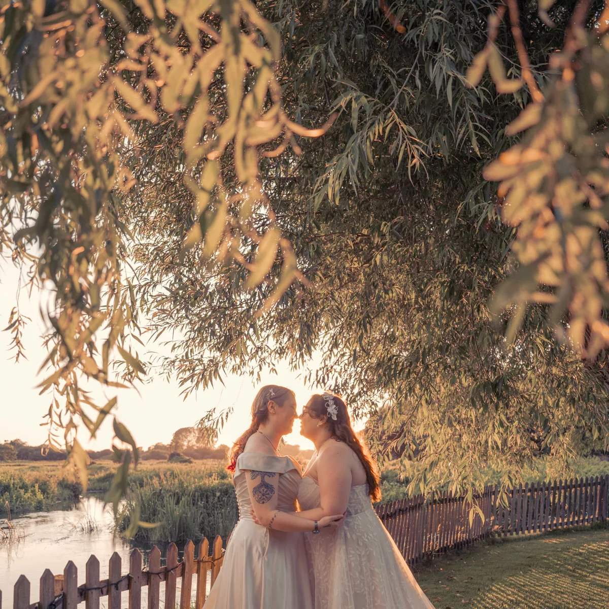 Two Brides in the outside wedding area under the trees at Sopley Mill at sunset