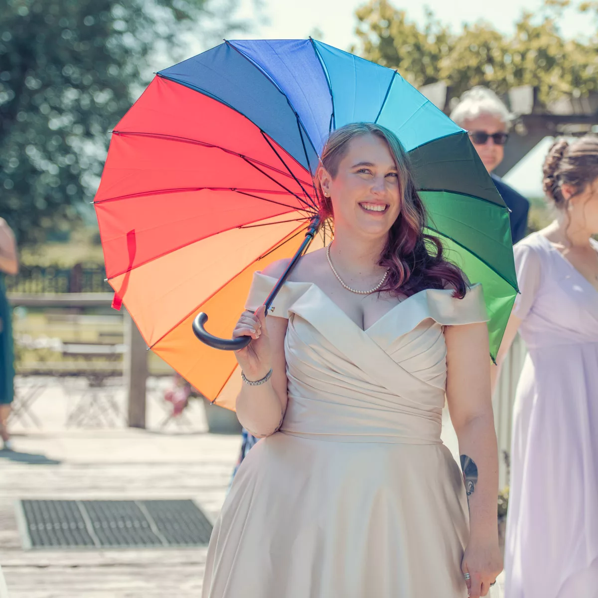 Bride with Gay Pride coloured umbrella during wedding at Sopley Mill